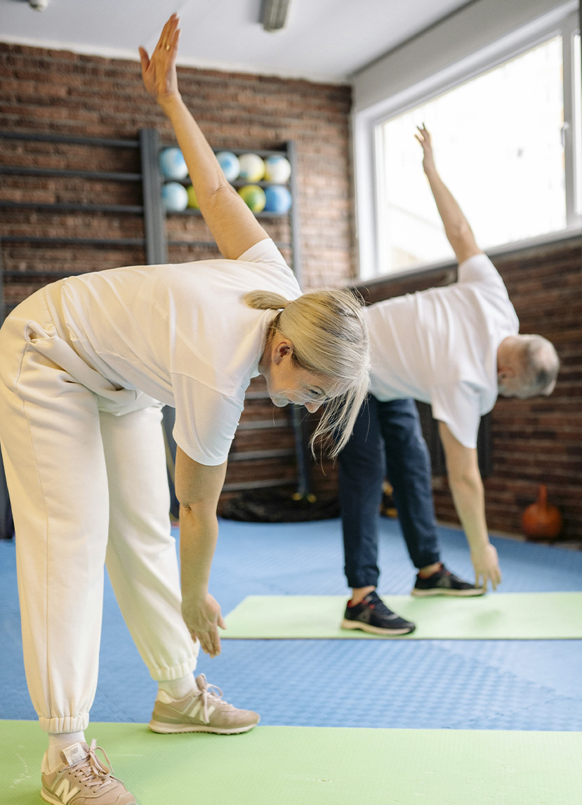 Older couple stretching body and muscles on green mat